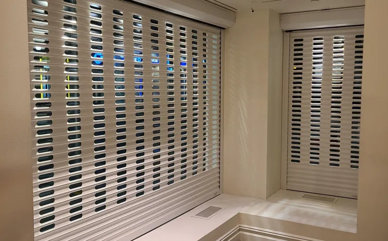 Close view of aluminum security grille perforations across two commercial openings